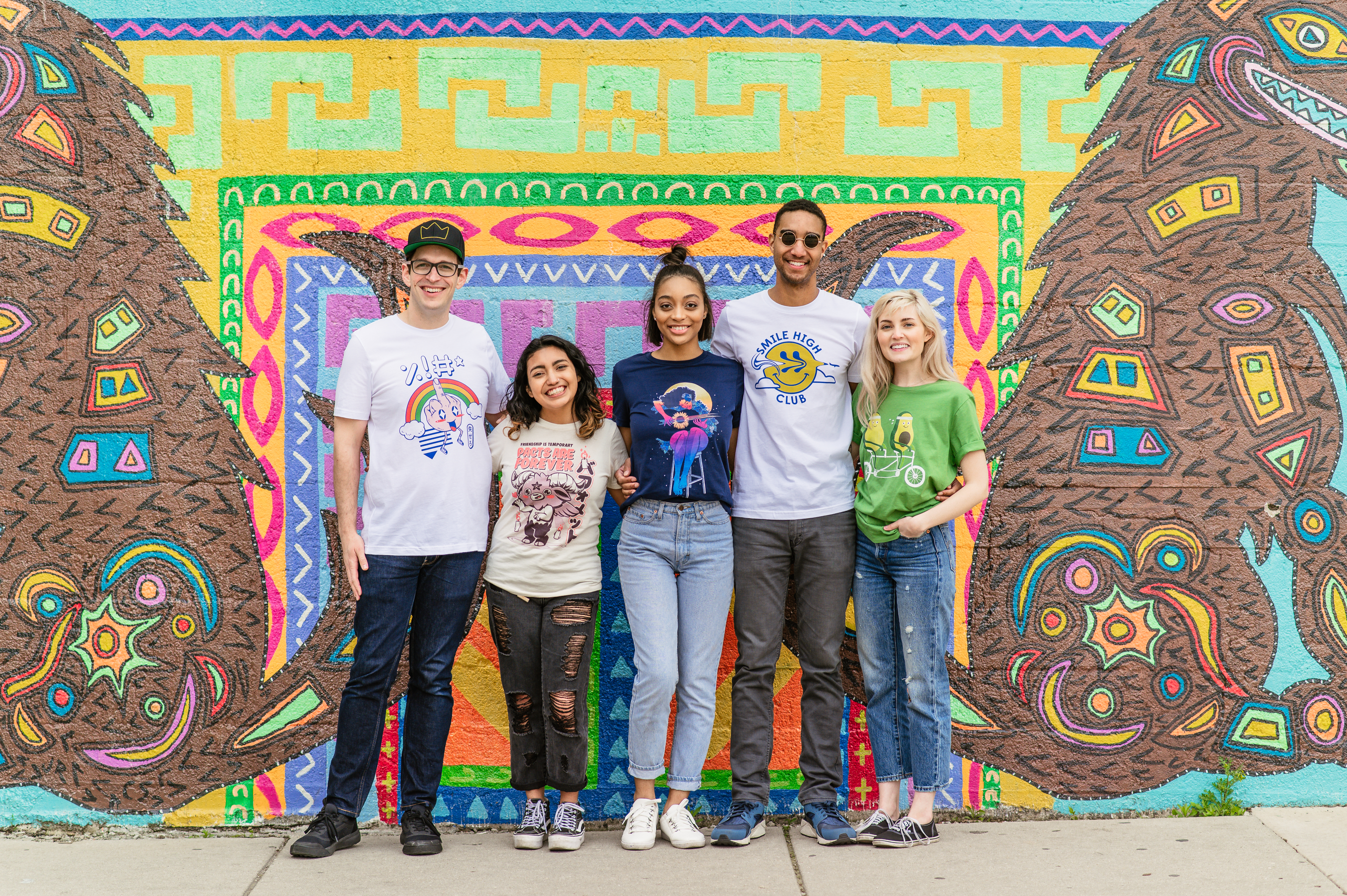 Guys and girls wearing t-shirts in front of mural